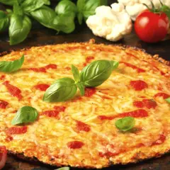 Pyszna pizza z kalafiora, z ciągnącym się serem, pomidorami i świeżą bazylią. Obok leżą pomidory i różyczki kalafiora.