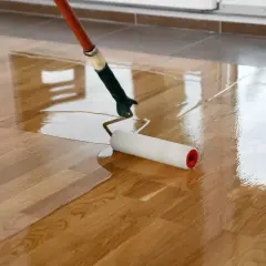 Application d'une couche de vernis pour vitrifier un parquet en bois, lui donnant un aspect brillant et protecteur.