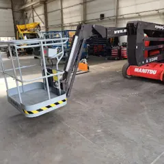 Czerwony podnośnik koszowy Manitou gotowy do pracy w hali.
