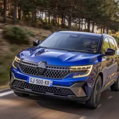 Blå Renault Austral kör på en slingrande väg genom en skog. Inga problem med denna bil, bara ren körglädje.
