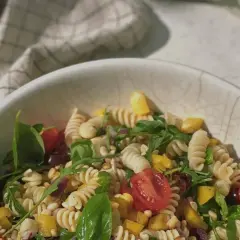 Leckerer Weight Watchers mediterraner Pastasalat mit Fusilli, Kirschtomaten, Rucola und gelber Paprika in einer Schüssel.