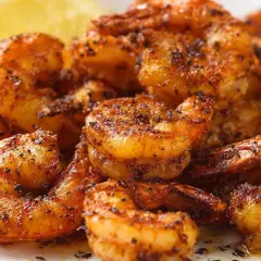 Chrupiące krewetki z airfryer, przyprawione i gotowe do podania z cytryną.