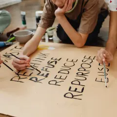 Niños pintan un cartel sobre la **competencia ciudadana LOMCE** y el reciclaje: "RETHINK, REFUSE, REDUCE, REPURPOSE, REUSE, RECYCLE".