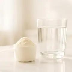 Un misurino di polvere bianca accanto a un bicchiere d'acqua, una sana alternativa alle proteine in polvere.