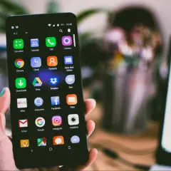 Dłoń trzyma smartfon z widocznym schowkiem w telefonie, pełnym ikon aplikacji, takich jak Gmail, Google i Instagram.