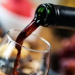 Mętne wino leje się z butelki do kieliszka. Ciemny płyn tworzy wiry, zapowiadając bogaty smak.
