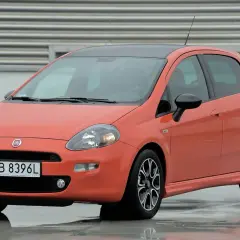 Pomarańczowy Fiat Punto na mokrej nawierzchni. Zwróć uwagę na jego kompaktowe fiat punto wymiary, idealne do miasta.