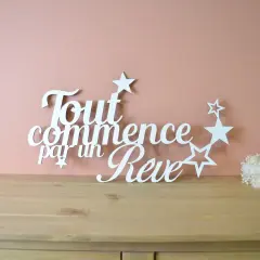 Une **lettre en bois blanc** forme la phrase "Tout commence par un Rêve", ornée d'étoiles. Un petit bouquet de fleurs séchées est posé à droite.