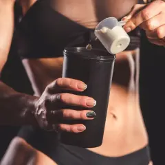 Kreatyna a białko: sportowiec dodaje proszek do shakera.