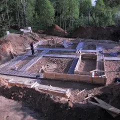Prace budowlane w toku: trwa zalewanie fundamentów domu. Widać zbrojenie i szalunki.