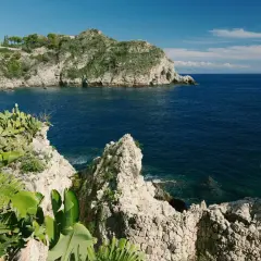 Scogliera verdeggiante e mare blu intenso al lido Isola Bella Taormina.