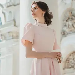 Elegancka kobieta w pudrowej sukience, idealna inspiracja, jak się ubrać na chrzciny jako gość kobieta.