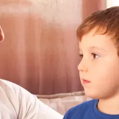 Matka z uwagą patrzy na syna, który słucha jej słów.