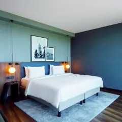 Nowoczesny pokój w **Radisson Blu Hotel Rostock** z wygodnym łóżkiem, dwoma obrazami na ścianie i stylowymi lampami.