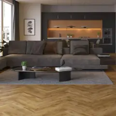 Nowoczesny salon z szarą sofą i ciemną ścianą w tle, za którą widać kuchnię.
