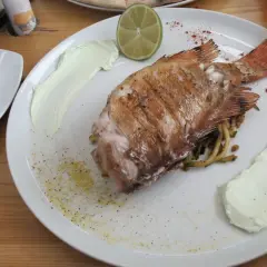 Ryba z grilla z sosem i limonką na talerzu w karczmie krynickiej Krynica Morska.