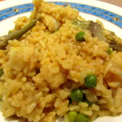 Arroz con bacalao y alcachofas, un plato reconfortante con guisantes verdes y trozos de pescado blanco.