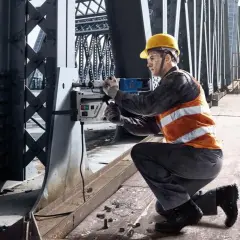 Pracownik na moście używa wiertarki magnetycznej Bosch do prac konstrukcyjnych.