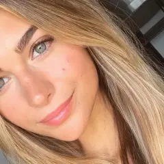 Uśmiechnięta dziewczyna z zielonymi oczami i włosami w odcieniu sombre blond.