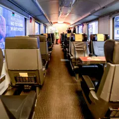 Wnętrze wagonu kolejowego, widok na miejsce połączenia wagonów. Puste siedzenia czekają na pasażerów.