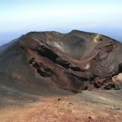 Crateri dell'Etna, un paesaggio lunare da esplorare con la propria auto. Rocce vulcaniche rosse e nere sotto un cielo azzurro.