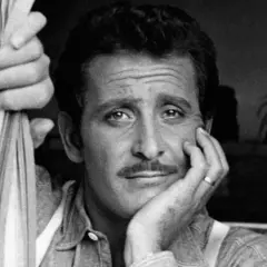 Domenico Modugno, con la mano appoggiata al viso, guarda pensieroso, mentre l'altra mano stringe delle corde.