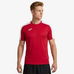 Mężczyzna w czerwonej koszulce piłkarskiej z białymi rękawami i logo Joma.