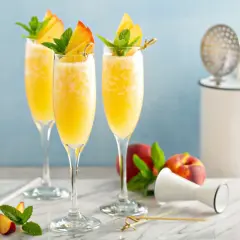 Orzeźwiający mimoza drink z brzoskwinią i miętą, idealny na letnie popołudnie.