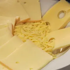 Assiette de fromages variés, dont des tranches d'Emmental avec ses trous caractéristiques, et du Gruyère râpé. La différence entre gruyère et emmental est subtile.