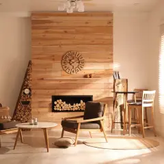 Salón acogedor con chimenea de madera, sillones, mesa y estantería. Lámparas estilo rústico moderno iluminan el espacio.