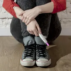 Młoda dziewczyna w dżinsach i trampkach trzyma test ciążowy. To trudny moment, kiedy dzieci mają dzieci.