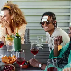 Vänner firar 30 års fest tema med en lek där lappar sitter på deras pannor. De skrattar och gissar.