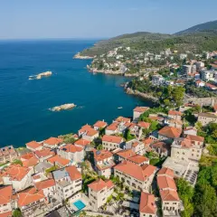 Widok na malownicze miasteczko Ulcinj z czerwonymi dachami, otoczone zielonymi wzgórzami i błękitnym morzem. Odkryj atrakcje tego nadmorskiego kurortu.
