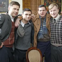Czterech młodych mężczyzn, część obsady "Czasu Honoru", pozuje do zdjęcia w eleganckich strojach.