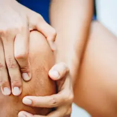Hände umfassen ein Knie, das auf Schmerzen im Bereich des pes anserinus superficialis und profundus hindeutet.