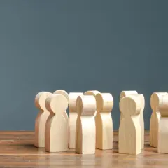Una figura rossa si distingue da un gruppo di figure di legno. A volte le persone cambiano, emergendo dalla massa.