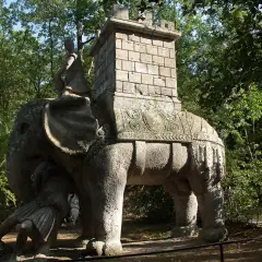 Elefante di pietra con guerriero e torre nel viterbo giardino dei mostri. Un'antica creatura che emerge dal verde.