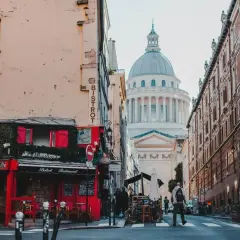 Urokliwa ulica w dzielnicy łacińskiej Paryża z czerwonym bistro i majestatycznym Panteonem w tle.