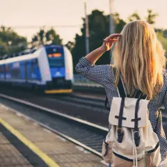 Dziewczyna z plecakiem czeka na pociąg, który zabierze ją do miast nad morzem.