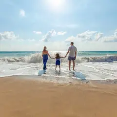 Rodzina cieszy się wczasy nad morzem z dzieckiem blisko plaży. Słońce, fale i piasek tworzą idealne tło dla wspólnych chwil.