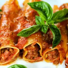 Cannelloni di carne ricetta della nonna, ripieni di ragù e conditi con sugo rosso e basilico fresco. Un piatto che sa di casa.