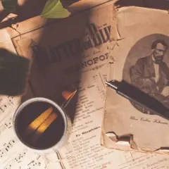 Sepia fotografia. Stare nuty, filiżanka kawy z pomarańczą i pióro.