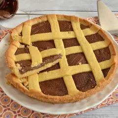 Deliziosa crostata alla Nutella con una fetta tagliata, pronta per essere gustata. Un vasetto di Nutella è visibile sullo sfondo.