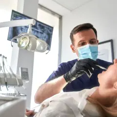 Dentista esamina un paziente, con un occhio attento alla salute orale. Un sorriso sano vale più di un bonus dentista 500 euro.