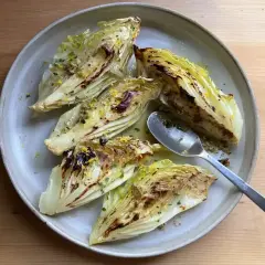 Grilla spetskål med citron och örter, serverad på en ljusgrå tallrik med en sked.