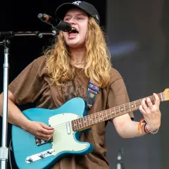 Mona på scen, sjunger och spelar gitarr med en blå Fender.
