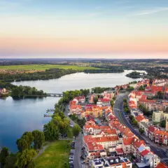 Widok na miasto w krainie wielkich jezior o zachodzie słońca. Domy z czerwonymi dachami, jezioro i zieleń.