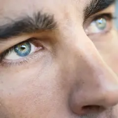 Primer plano de los ojos de un hombre, destacando sus cejas pobladas y el iris azul verdoso.