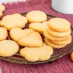 Deliziosi dolci da fare in casa, biscotti a forma di cuore e fiori su un cestino di metallo, pronti per essere gustati.