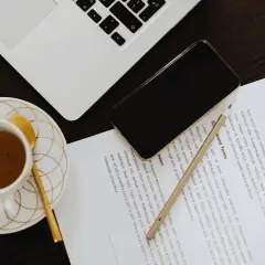 Złote nożyczki, filiżanka kawy i telefon leżą obok umowy. Gdzie zgłosić nabycie nieruchomości? Sprawdź warunki umowy.